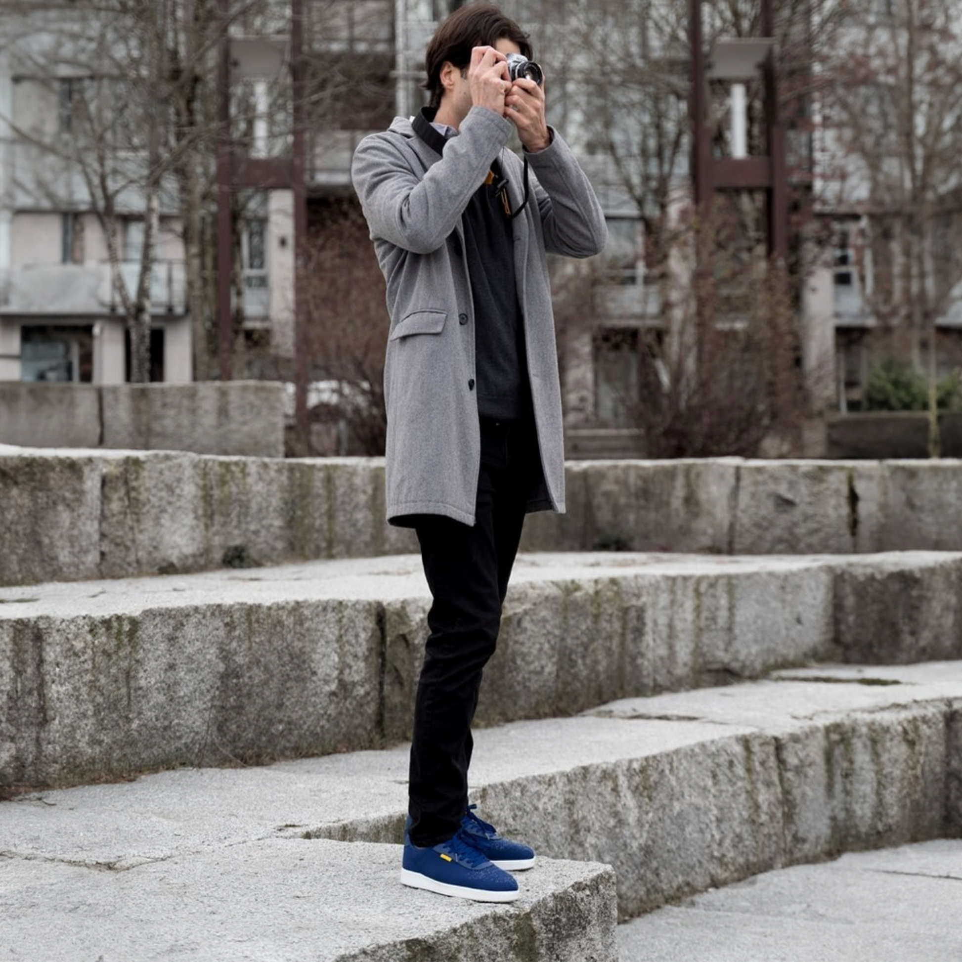 Man taking a photo with a camera on stone steps outdoors